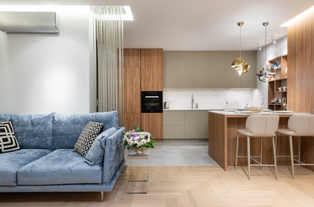 Furnished home interior with a blue couch and a kitchen in the background